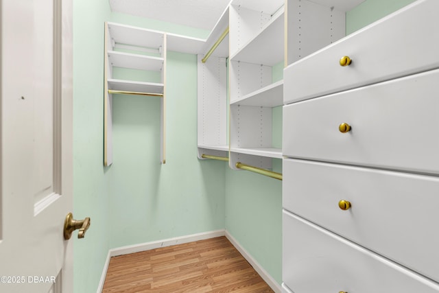 walk in closet with light hardwood / wood-style floors