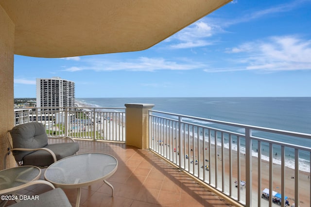 balcony featuring a view of the beach and a water view