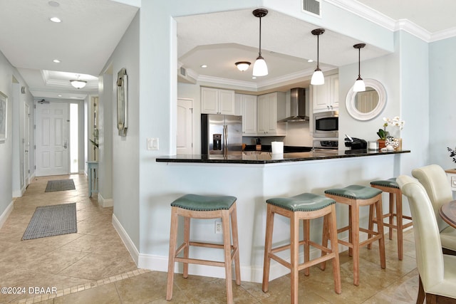 kitchen with white cabinetry, appliances with stainless steel finishes, pendant lighting, kitchen peninsula, and wall chimney exhaust hood