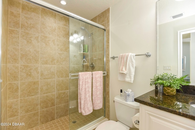 bathroom featuring a shower with door, vanity, and toilet