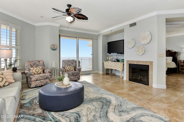 living room with a tile fireplace, ornamental molding, and plenty of natural light