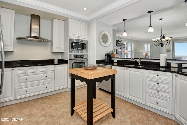 kitchen with wall chimney range hood, white cabinets, sink, and stainless steel appliances