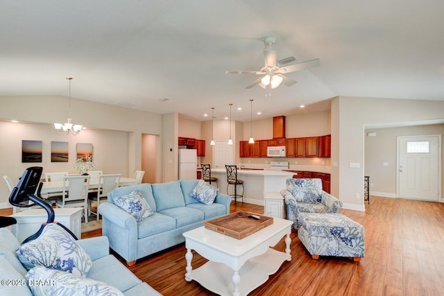 living area featuring light wood-style flooring, baseboards, vaulted ceiling, and ceiling fan with notable chandelier