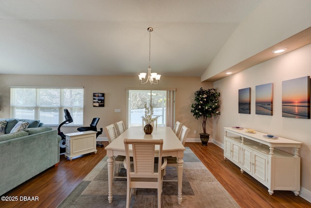 dining room featuring dark wood-style floors, a chandelier, vaulted ceiling, and baseboards