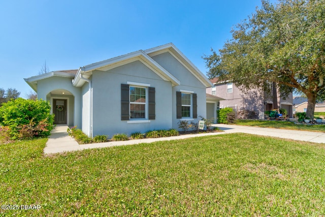 view of front of house featuring a front yard, driveway, and stucco siding