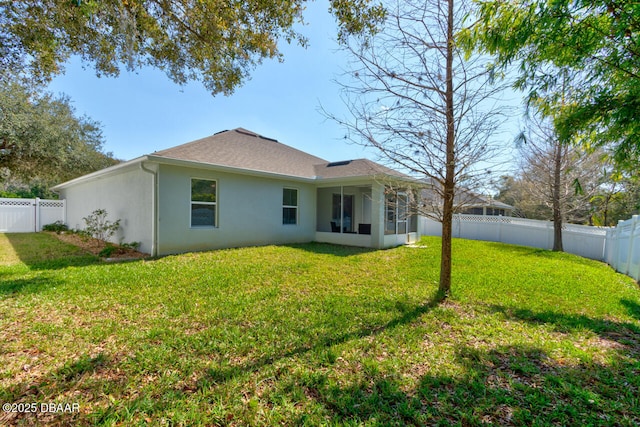 rear view of property with driveway, a lawn, a sunroom, a fenced backyard, and an attached garage