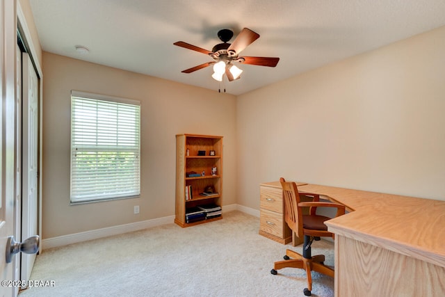 carpeted office featuring a ceiling fan and baseboards