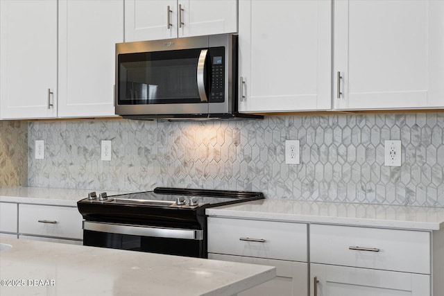 kitchen with decorative backsplash, white cabinets, range with electric cooktop, and light stone countertops