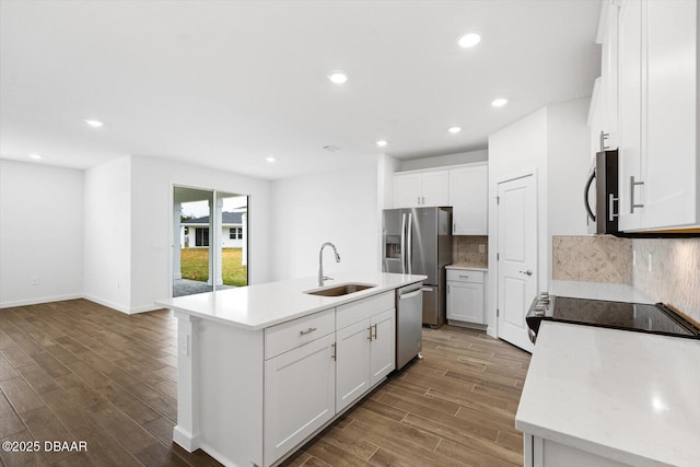 kitchen featuring appliances with stainless steel finishes, backsplash, white cabinets, and an island with sink