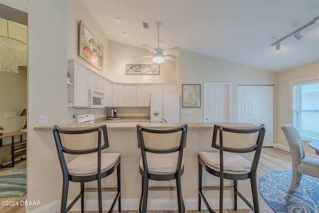 kitchen with lofted ceiling, kitchen peninsula, track lighting, white cabinetry, and white appliances