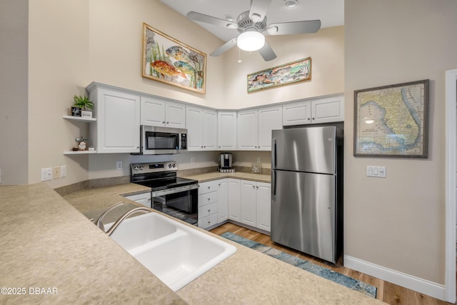 682 Middlebury Loop, New Smyrna Beach, FL 32168 - kitchen featuring stainless steel appliances, light wood-style flooring, a towering ceiling, a ceiling fan, and open shelves