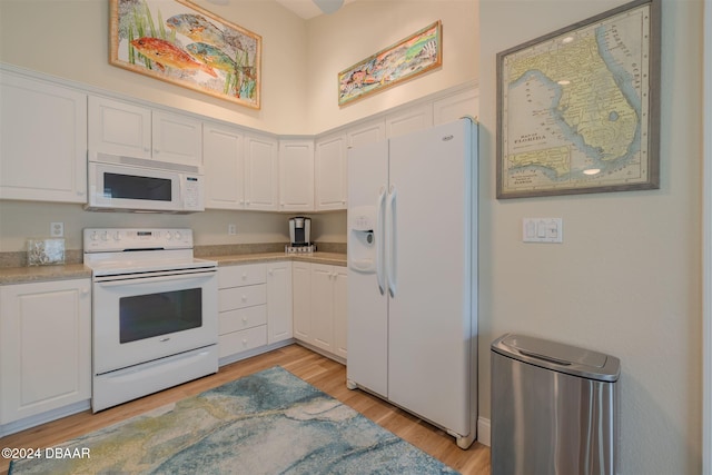 kitchen with white appliances, white cabinetry, and light hardwood / wood-style floors