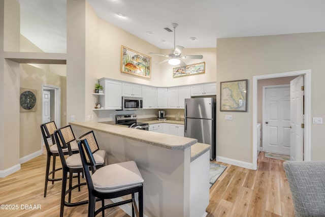 682 Middlebury Loop, New Smyrna Beach, FL 32168 - kitchen featuring stainless steel appliances, a peninsula, a high ceiling, white cabinetry, and ceiling fan