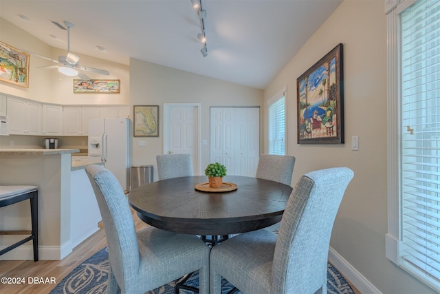 dining area featuring ceiling fan, rail lighting, light wood-type flooring, and vaulted ceiling