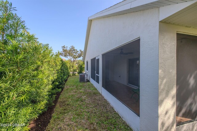 682 Middlebury Loop, New Smyrna Beach, FL 32168 - view of side of property with central AC unit, stucco siding, ceiling fan, a yard, and a sunroom