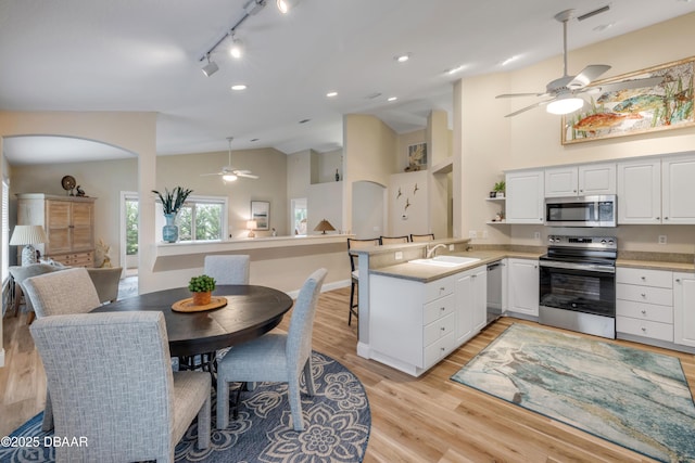 682 Middlebury Loop, New Smyrna Beach, FL 32168 - kitchen featuring stainless steel appliances, a ceiling fan, a peninsula, white cabinetry, and high vaulted ceiling