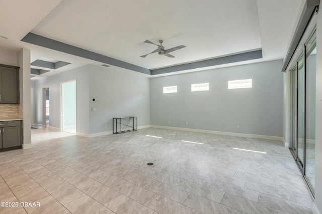 tiled spare room featuring a tray ceiling and ceiling fan