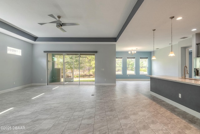 unfurnished living room featuring sink and ceiling fan with notable chandelier