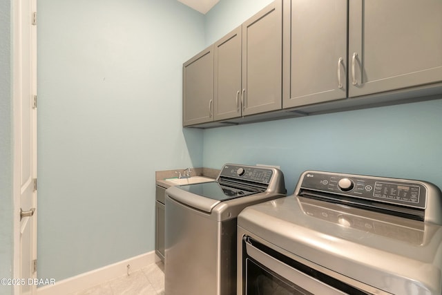 laundry area featuring washer and clothes dryer, cabinets, and light tile patterned flooring