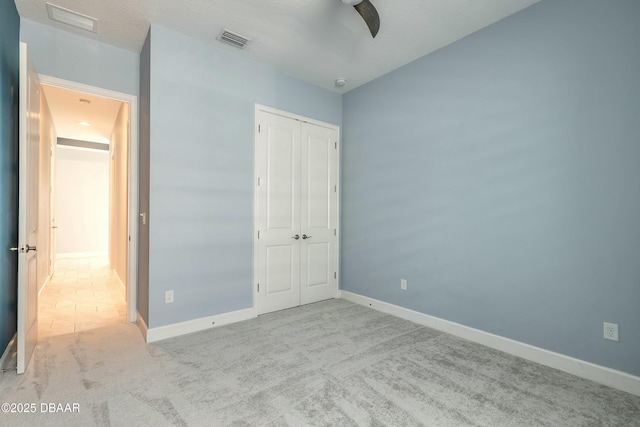 unfurnished bedroom with ceiling fan, light colored carpet, and a closet