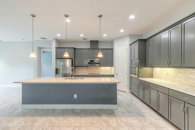 kitchen with stainless steel appliances, hanging light fixtures, sink, and a center island with sink