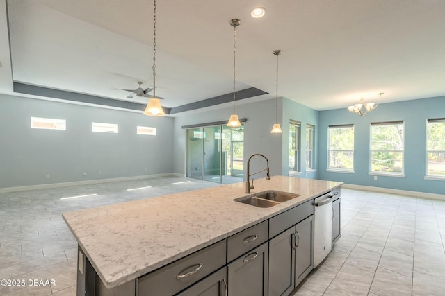 kitchen featuring sink, a wealth of natural light, light stone countertops, a center island with sink, and stainless steel dishwasher