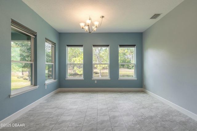 unfurnished room with a notable chandelier and a textured ceiling