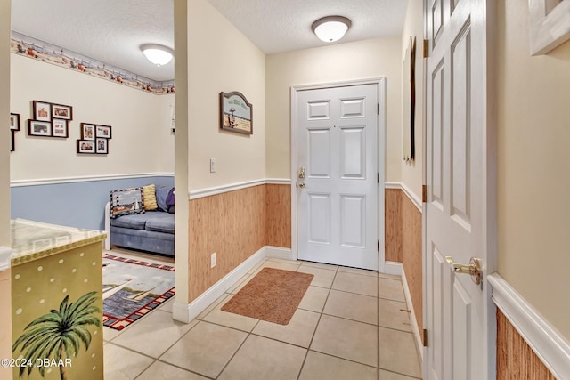 tiled foyer with a textured ceiling and wooden walls