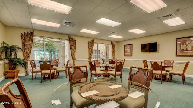 carpeted dining area featuring a paneled ceiling and plenty of natural light