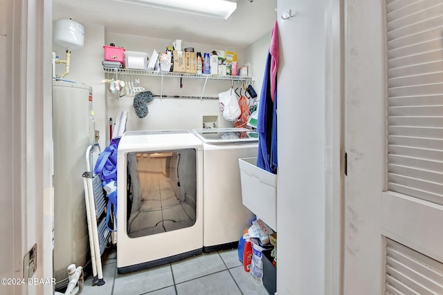 laundry room featuring water heater, washing machine and dryer, and light tile patterned floors