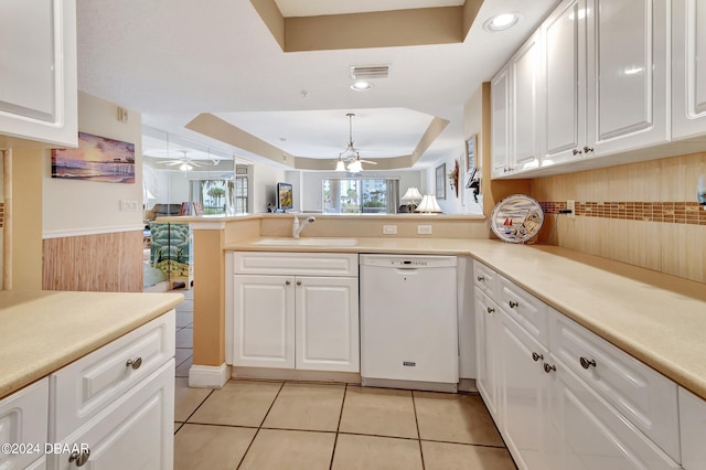 kitchen with a tray ceiling, sink, white cabinets, dishwasher, and kitchen peninsula