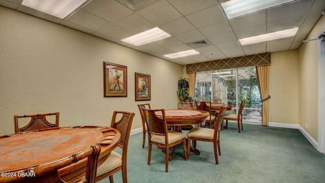 carpeted dining space featuring a paneled ceiling