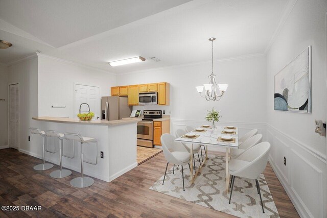 kitchen featuring hanging light fixtures, stainless steel appliances, dark hardwood / wood-style floors, a notable chandelier, and a kitchen bar