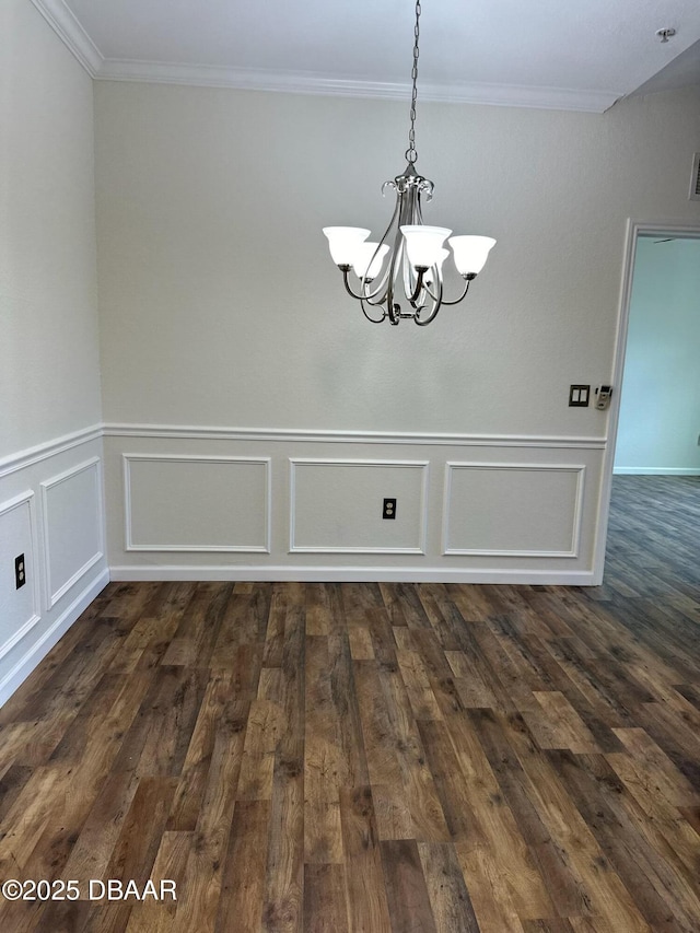 unfurnished dining area featuring ornamental molding, dark wood-type flooring, and an inviting chandelier