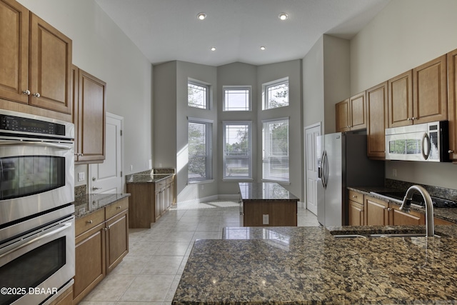 408 Chelsea Place Ave, Ormond Beach, FL 32174 - kitchen with a kitchen island, a high ceiling, dark stone counters, appliances with stainless steel finishes, and light tile patterned floors
