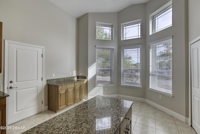 408 Chelsea Place Ave, Ormond Beach, FL 32174 - kitchen with light tile patterned floors, baseboards, a high ceiling, and brown cabinetry