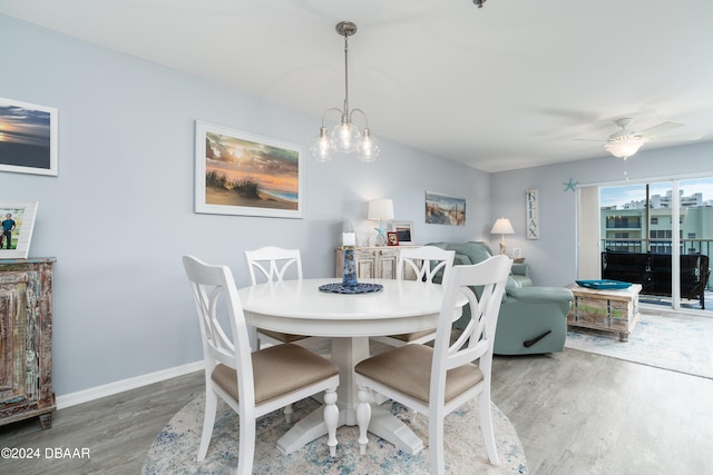 dining space with wood-type flooring and ceiling fan with notable chandelier