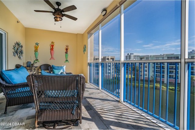 sunroom / solarium with ceiling fan and a water view