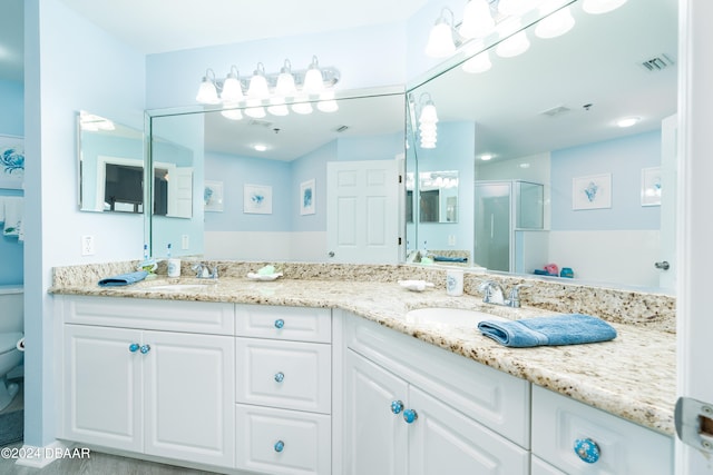 bathroom with toilet, vanity, and a shower with shower door