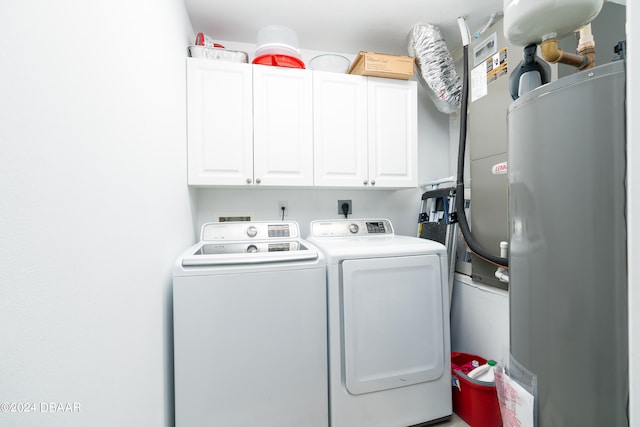 clothes washing area with cabinets, water heater, and independent washer and dryer