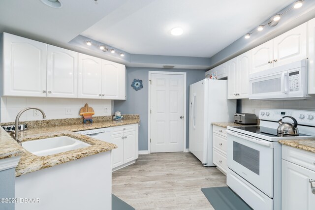 kitchen with light stone counters, white cabinetry, sink, light hardwood / wood-style floors, and white appliances