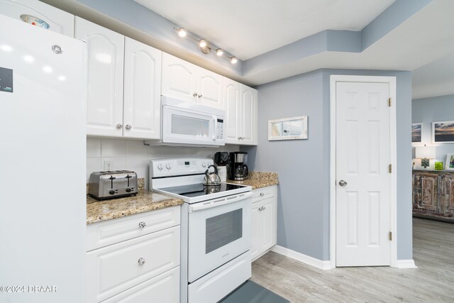 kitchen with tasteful backsplash, light stone counters, white cabinetry, light hardwood / wood-style floors, and white appliances