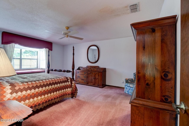 bedroom featuring a textured ceiling, ceiling fan, and light colored carpet