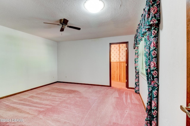 empty room with ceiling fan, light colored carpet, and a textured ceiling