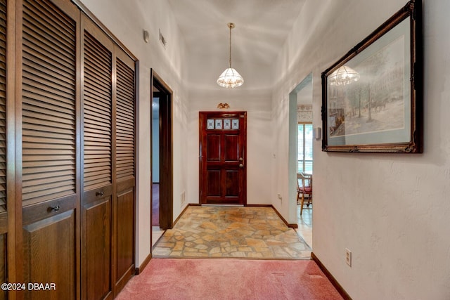 entrance foyer with light carpet and a chandelier