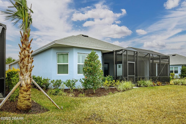 view of home's exterior with a yard and glass enclosure