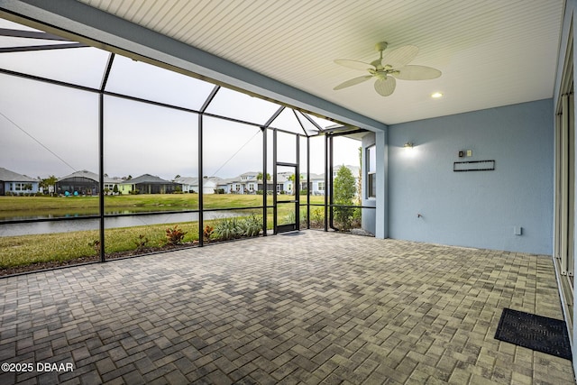 unfurnished sunroom with ceiling fan and a water view