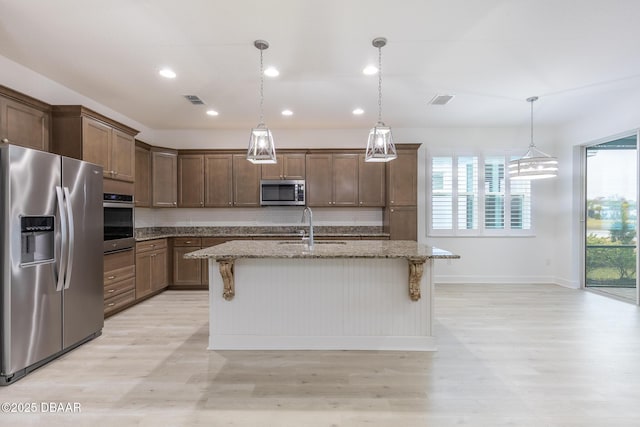 kitchen featuring a kitchen island with sink, sink, a kitchen breakfast bar, and appliances with stainless steel finishes