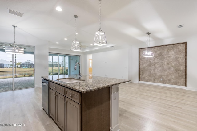 kitchen featuring pendant lighting, light stone countertops, sink, and a center island with sink