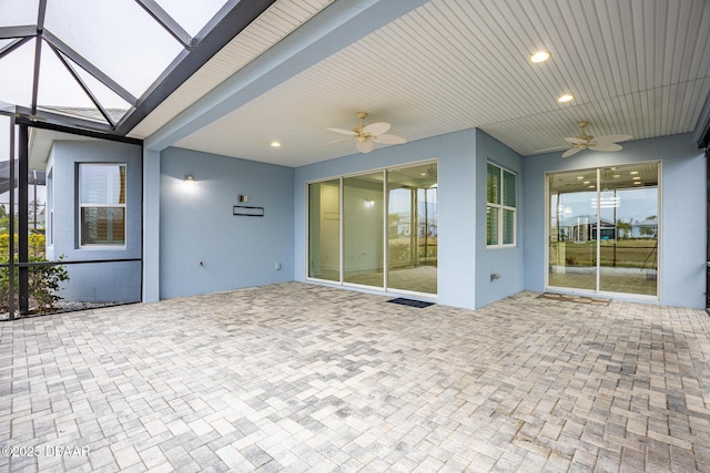 view of patio featuring ceiling fan and glass enclosure